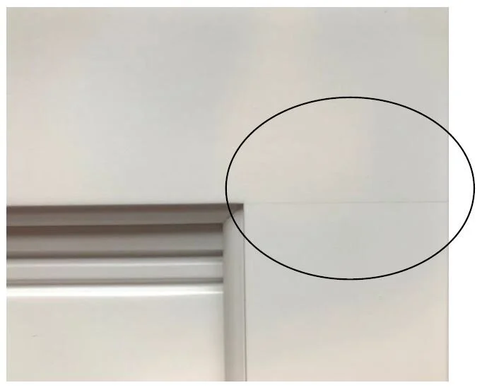 Small hairline crack at the joint of a painted cabinet door.