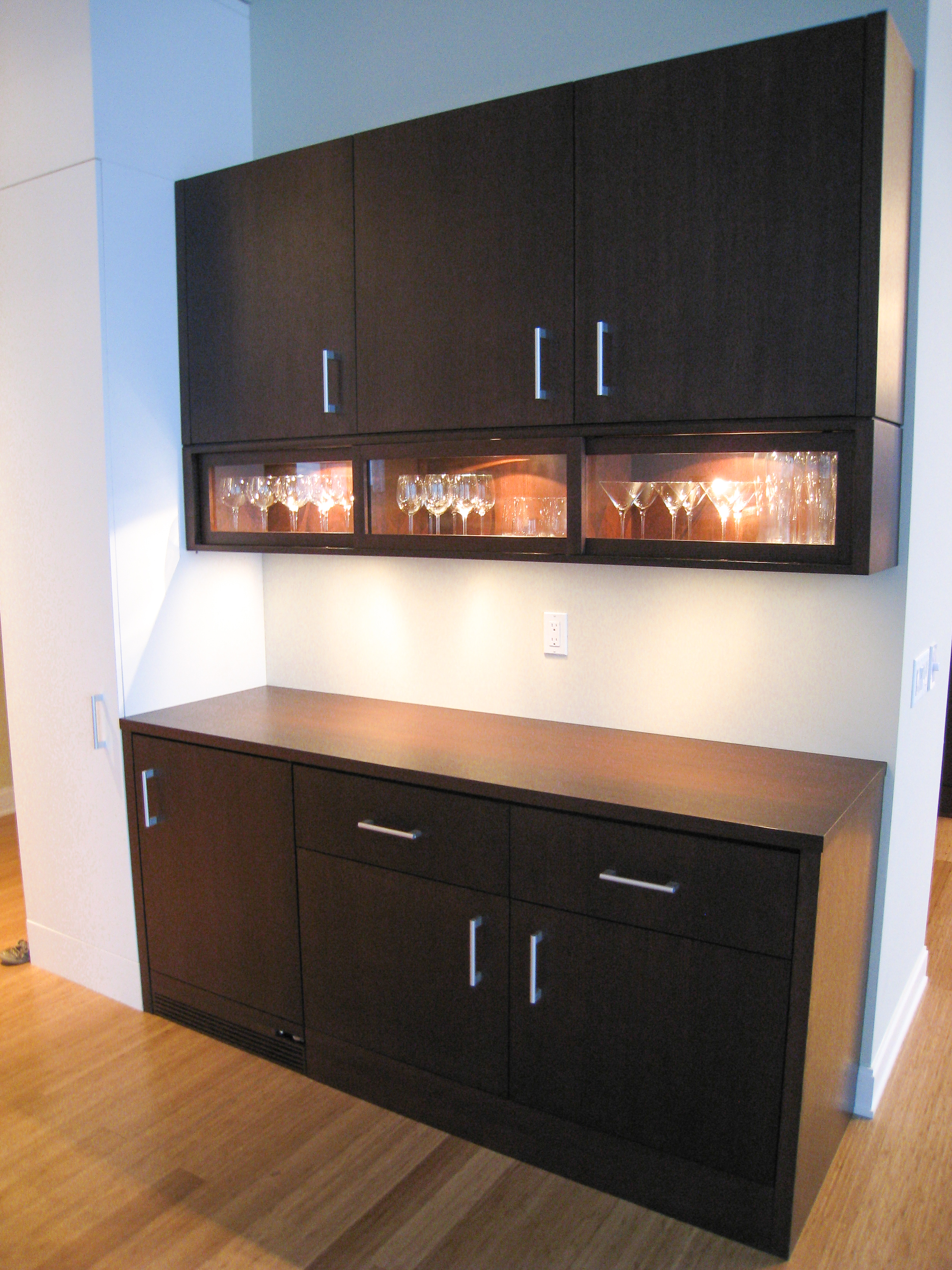 Espresso bar cabinet with amber-lit glass-front wine display and built-in bar storage