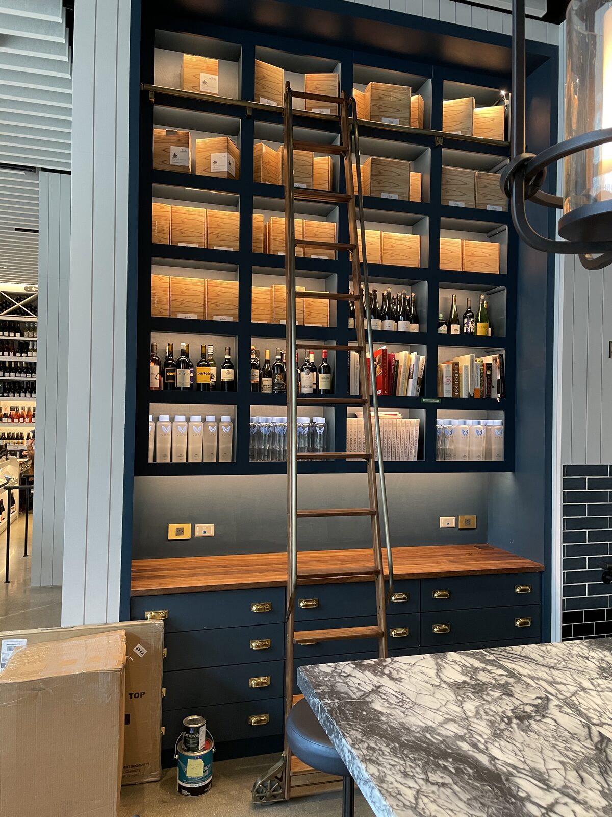 Commercial wine bar with navy cabinetry, library rolling ladder, and walnut bar counter