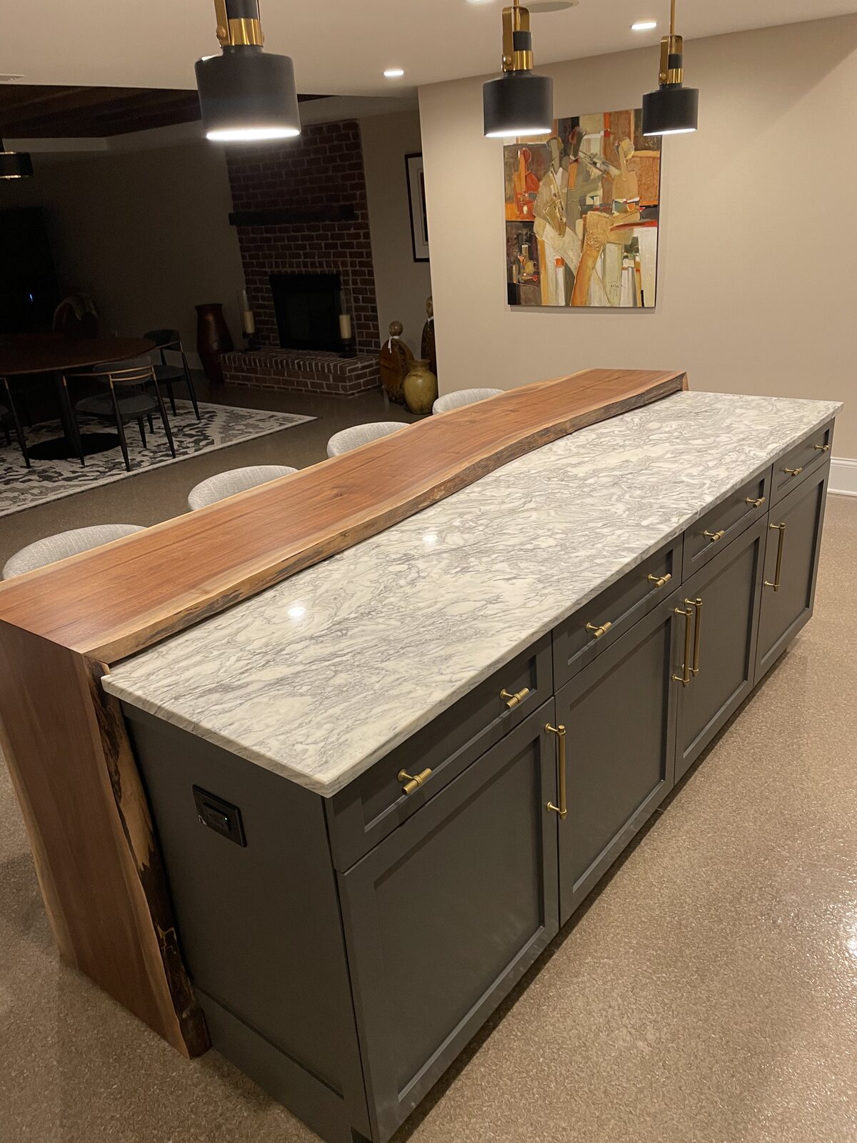 Wide view of custom walnut bar countertop in a dining and entertaining space with brick fireplace