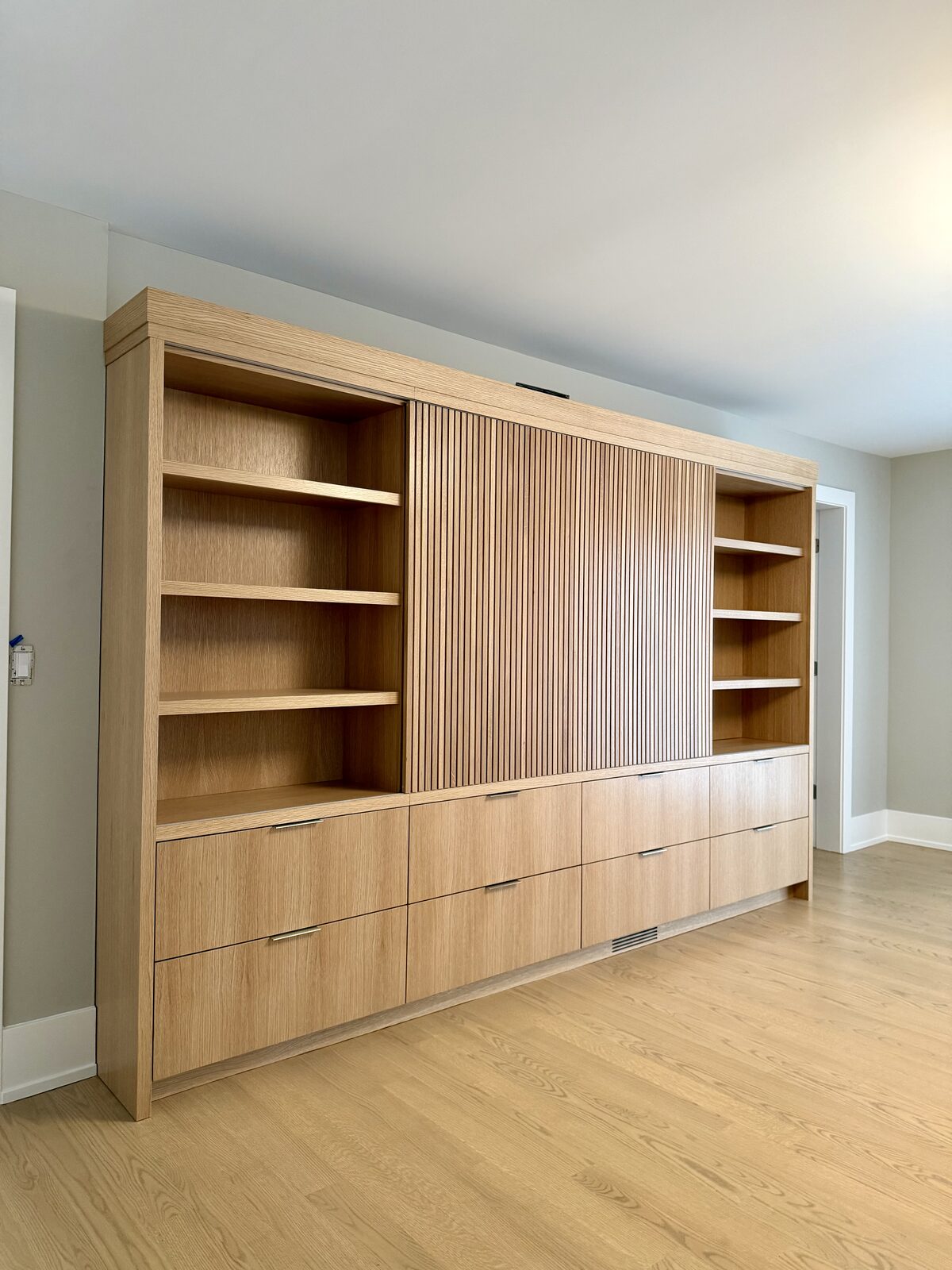 White oak bedroom wall unit with fluted sliding panel doors, full facade closed