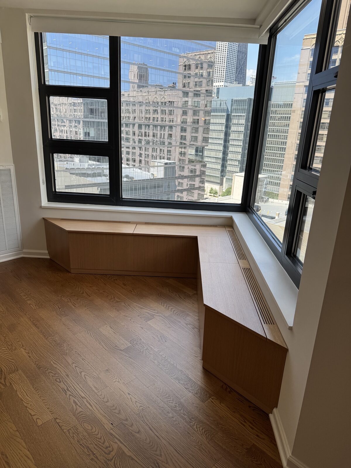 White oak L-shaped window bench built-in with Chicago highrise city skyline view