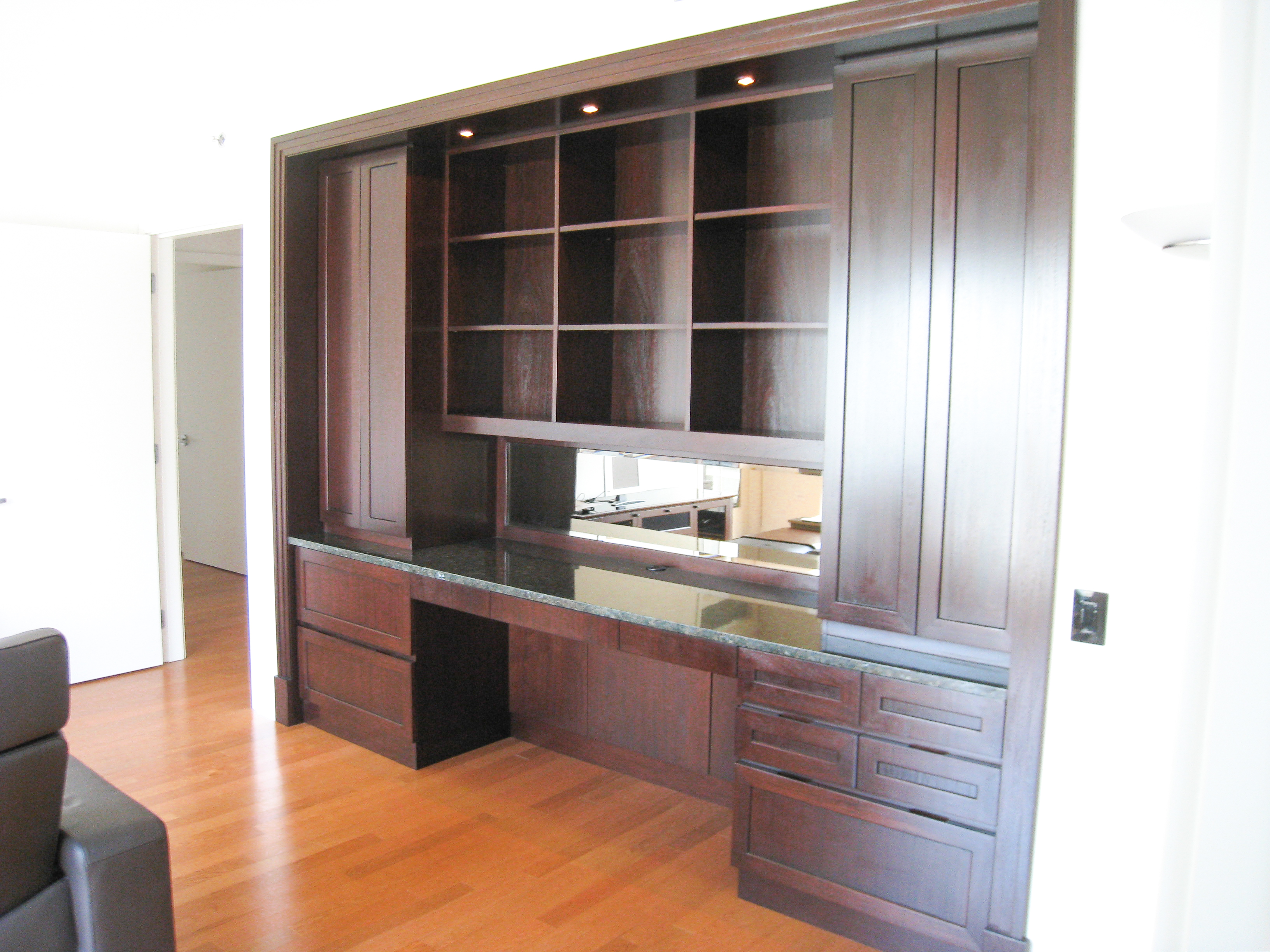 Traditional mahogany home office built-in with open upper cubbies, desk surface, and lower drawer storage