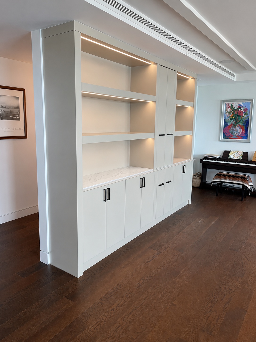 Large white painted built-in with open shelving, LED strip lighting, marble flush countertop, and lower door storage
