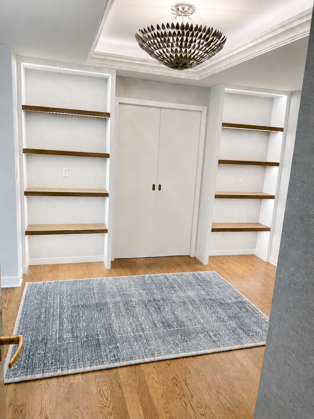 White painted flanking bookshelves with walnut shelf faces framing a doorway entry