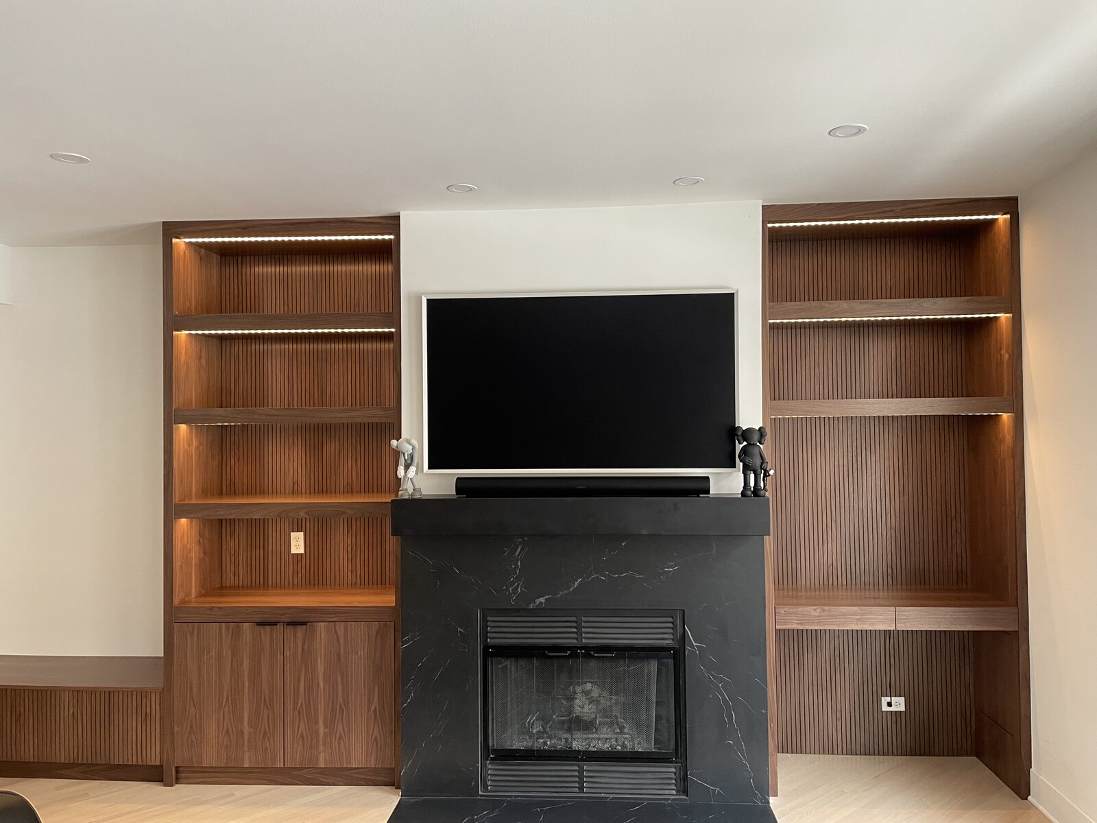 Walnut fluted media wall with black marble fireplace surround