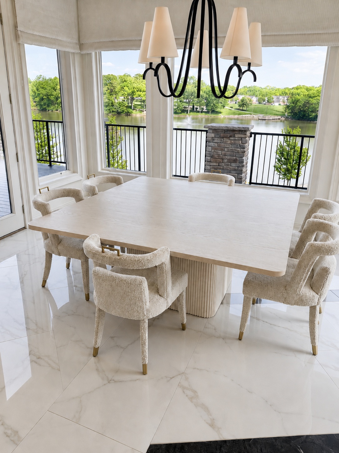 Limed oak square dining table with fluted pedestal base, surrounded by upholstered chairs, overlooking a lake
