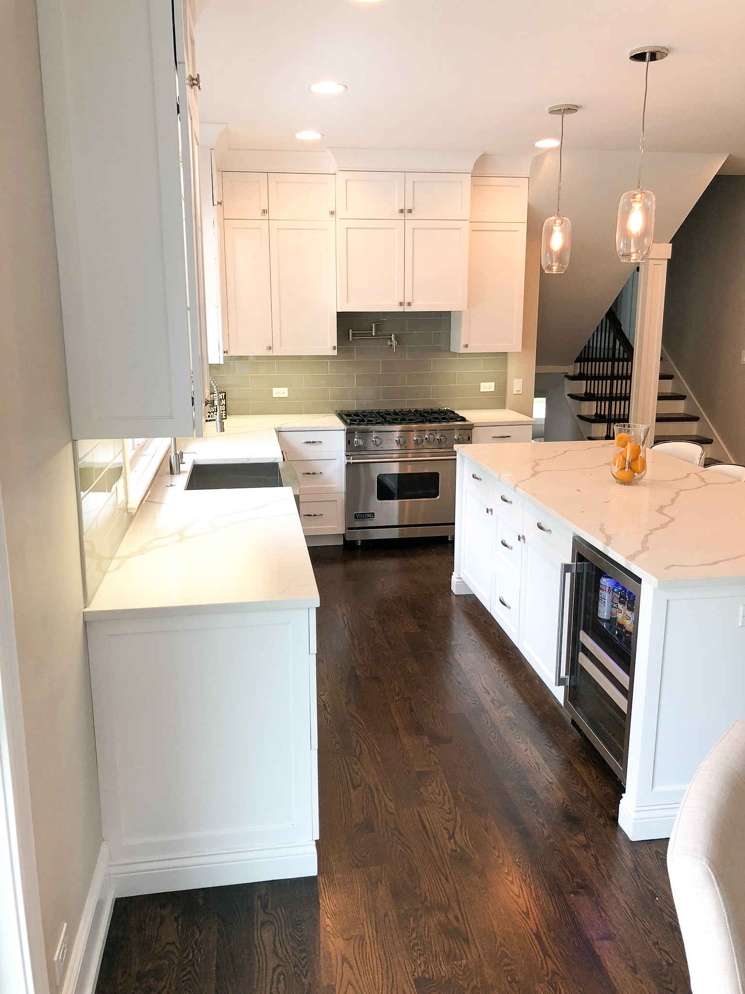 White shaker kitchen with ceiling-height cabinets, Viking range, and sage green tile backsplash