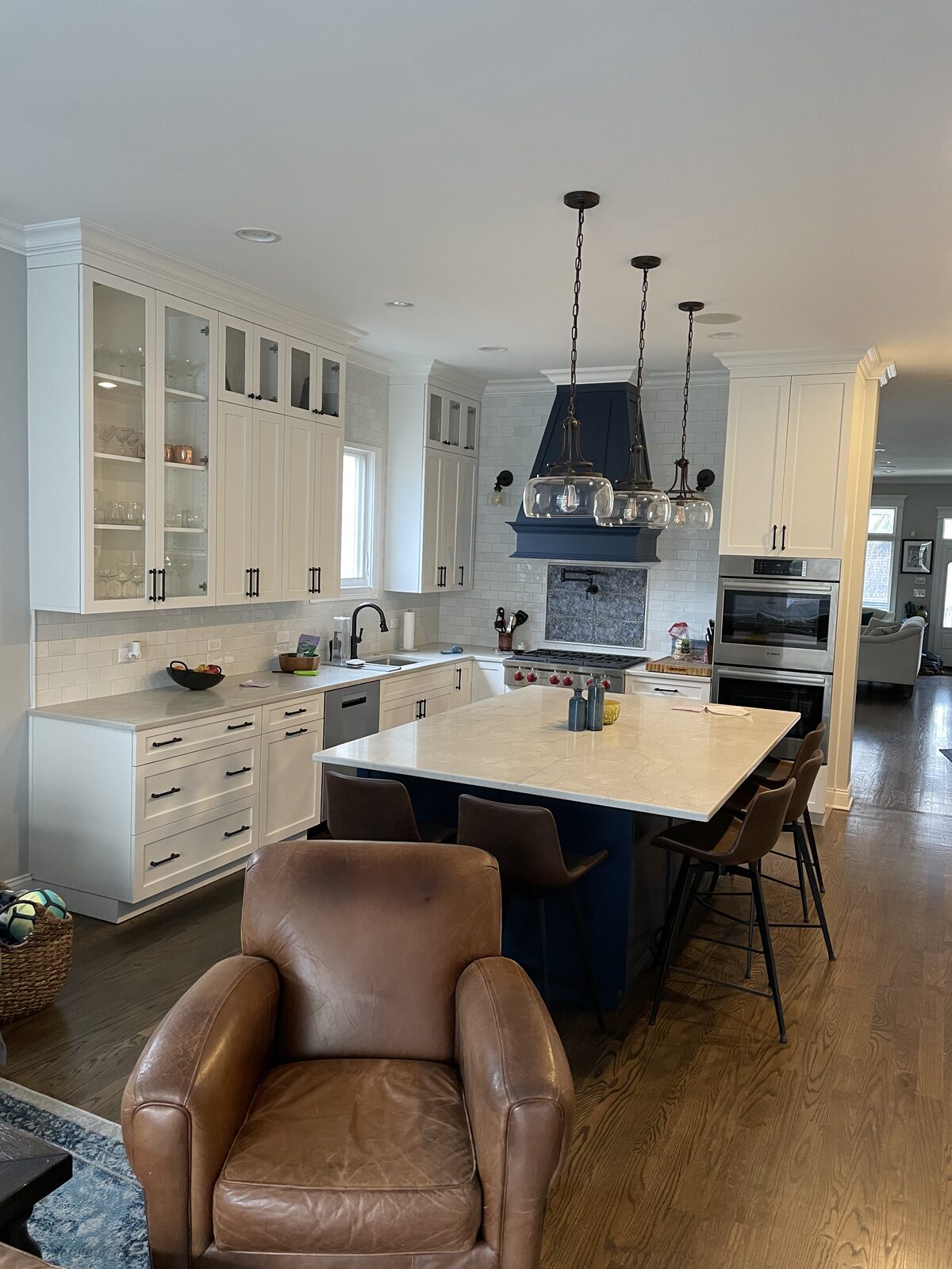 Navy blue kitchen island with Wolf range and matching blue custom hood, waterfall quartz countertop