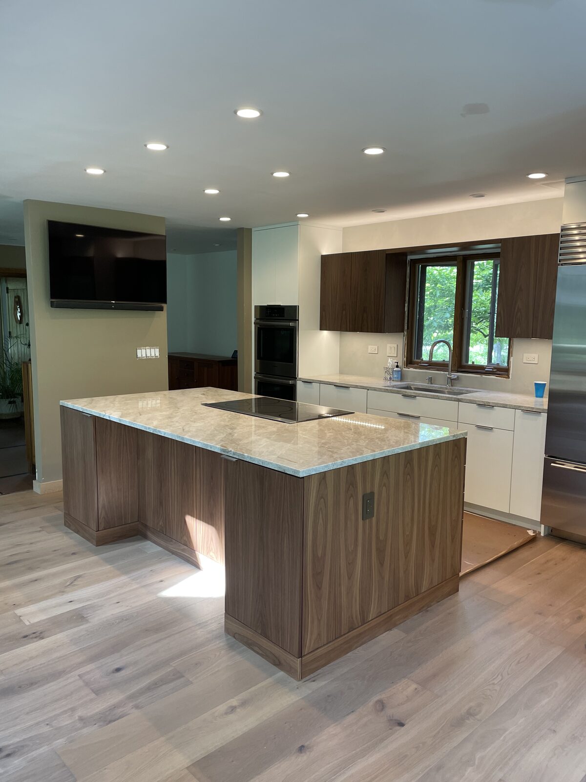 Walnut flat-panel island kitchen with SubZero refrigerator, induction cooktop, and marble countertops