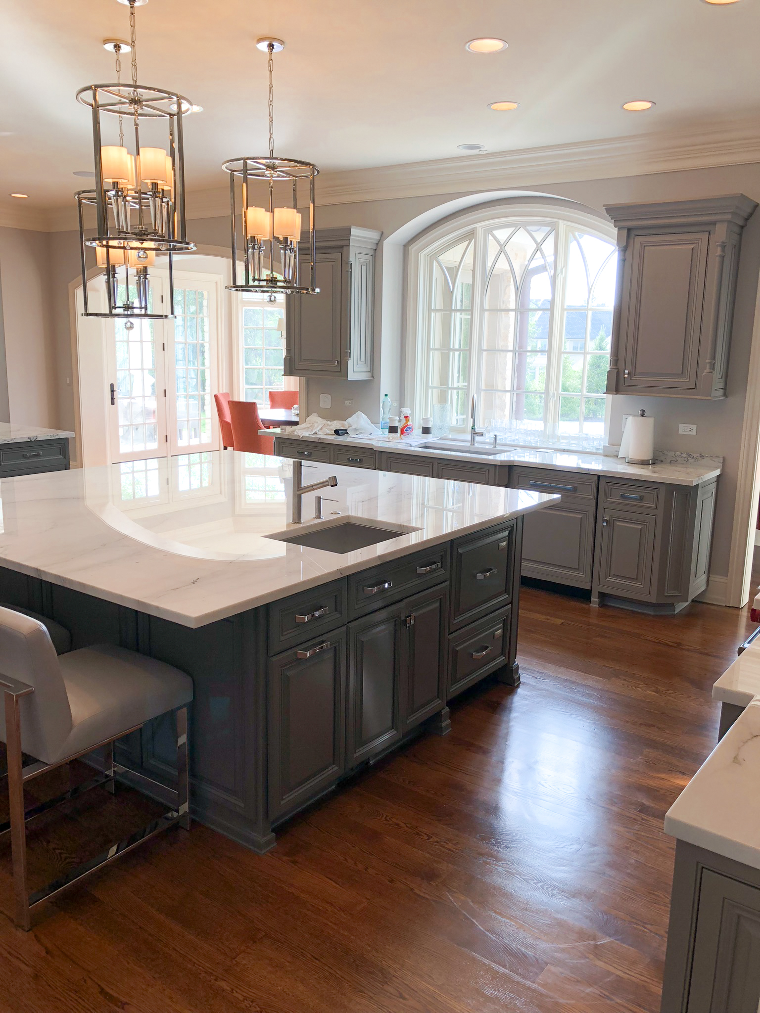 Gray shaker kitchen with marble island, lantern chandelier, and gothic arched window