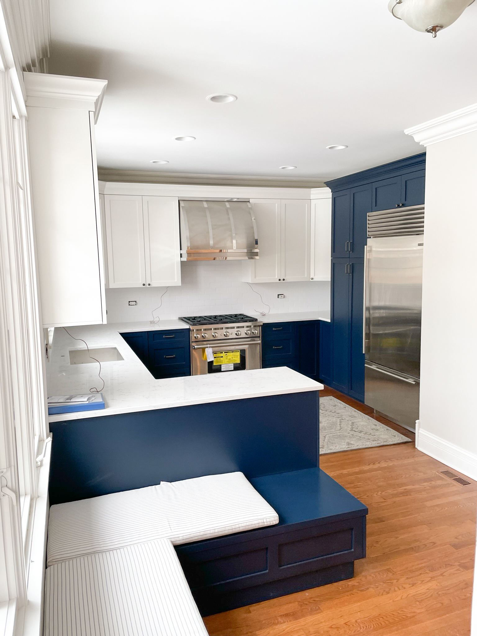 Navy and white kitchen with professional range, SubZero refrigerator, and built-in window bench