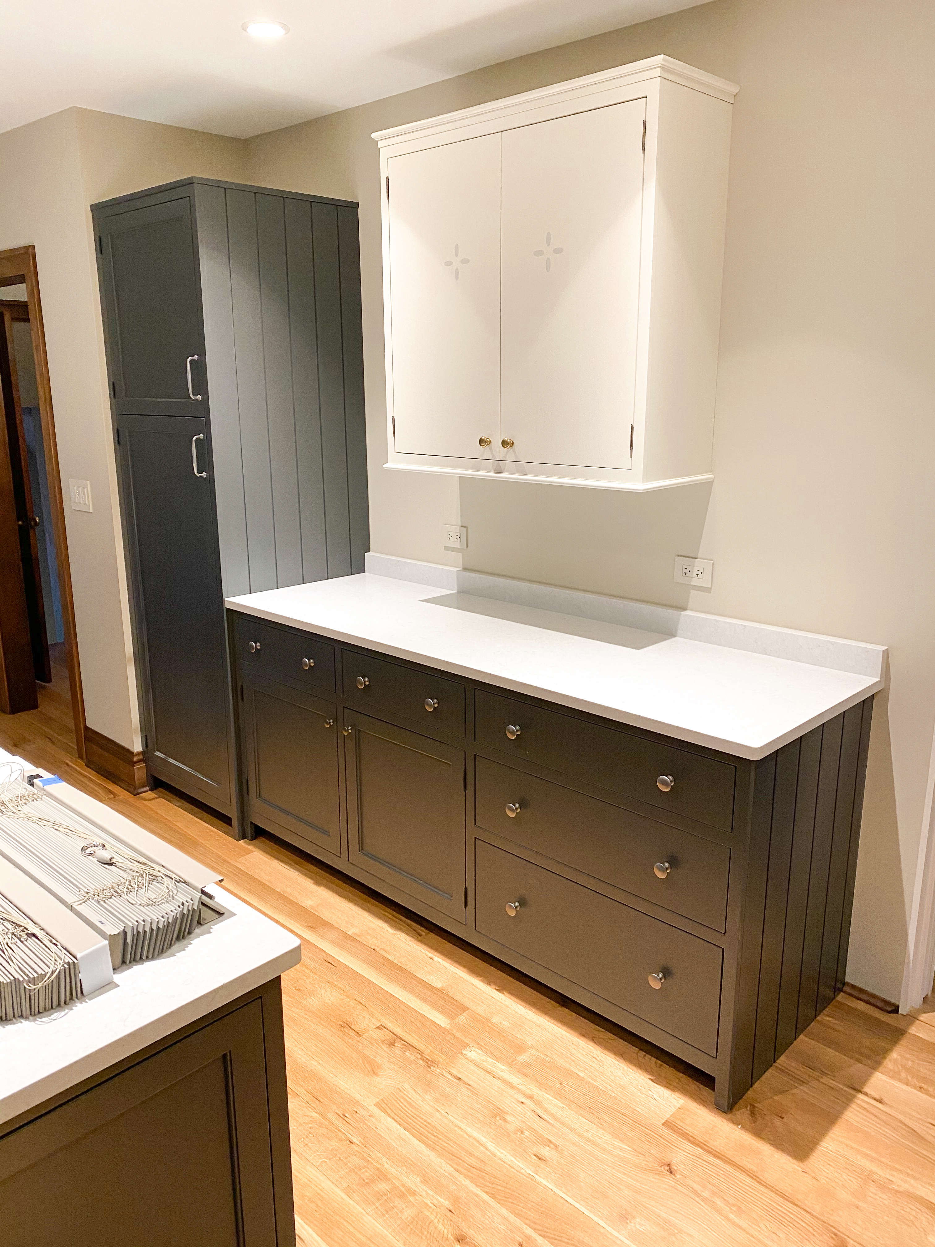 Dark gray painted lower kitchen cabinetry with white upper cabinet and cross-pattern door detail