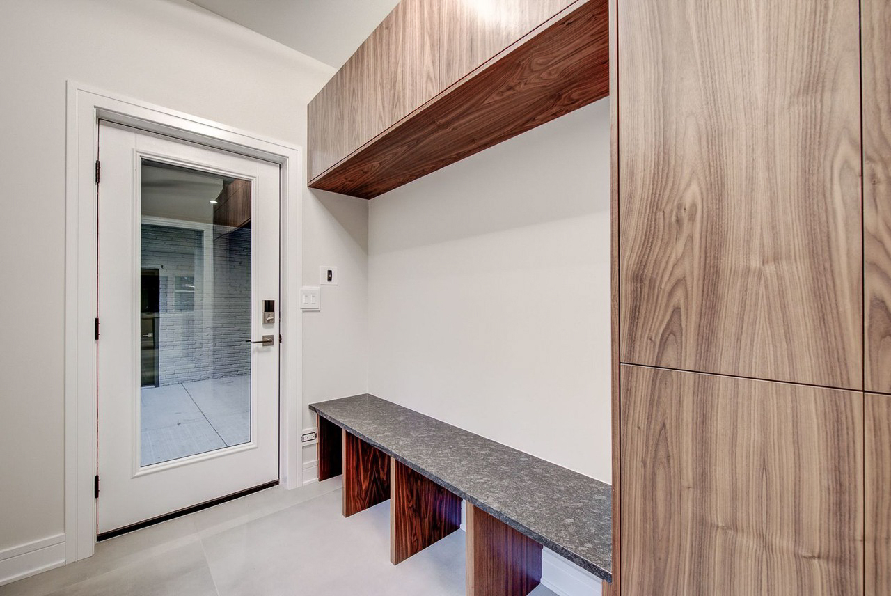 Walnut mudroom built-in with floating shelf above a granite-topped bench
