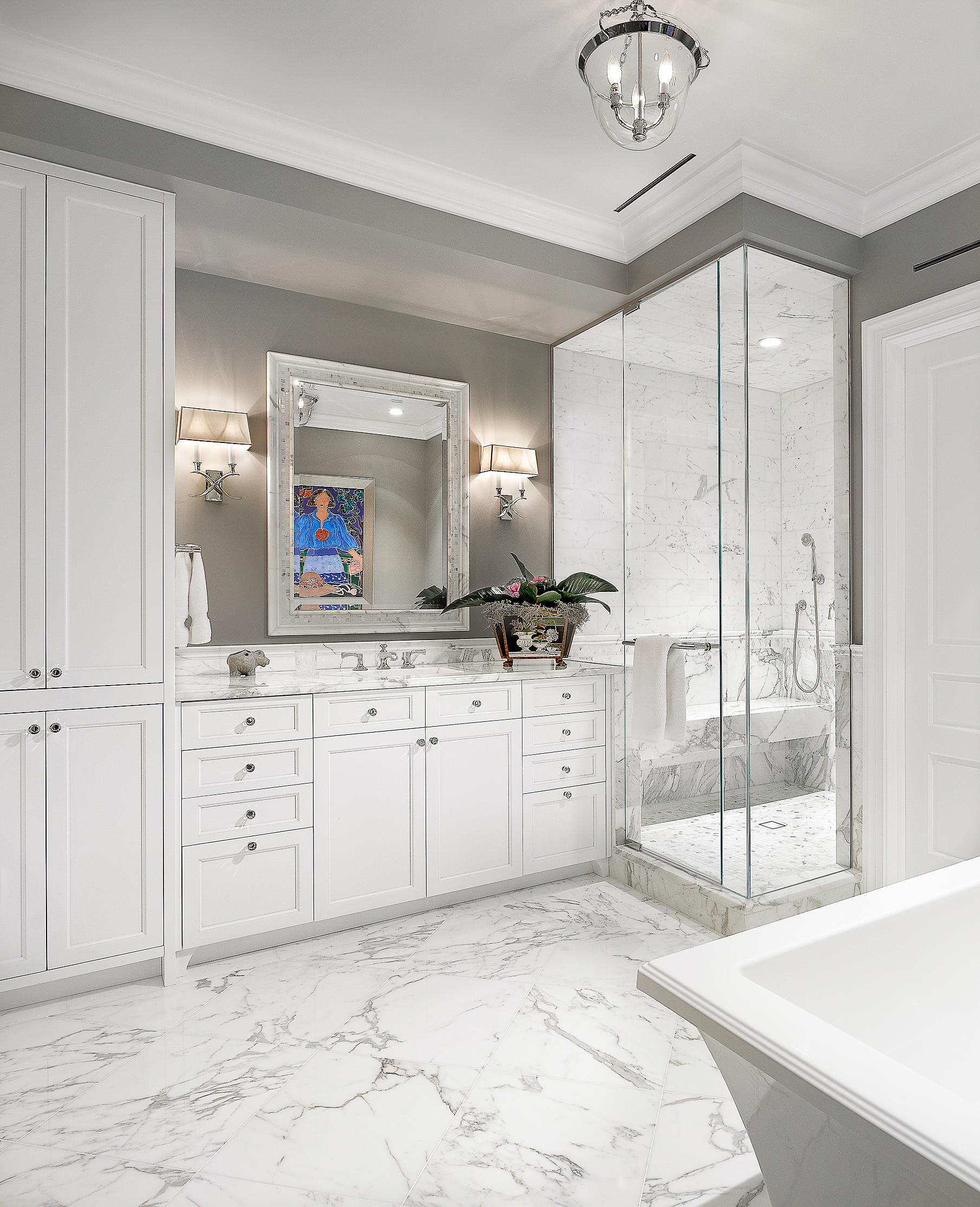 Luxury primary bath with white shaker vanity, crystal knobs, Calacatta marble top, built-in linen tower, and marble shower