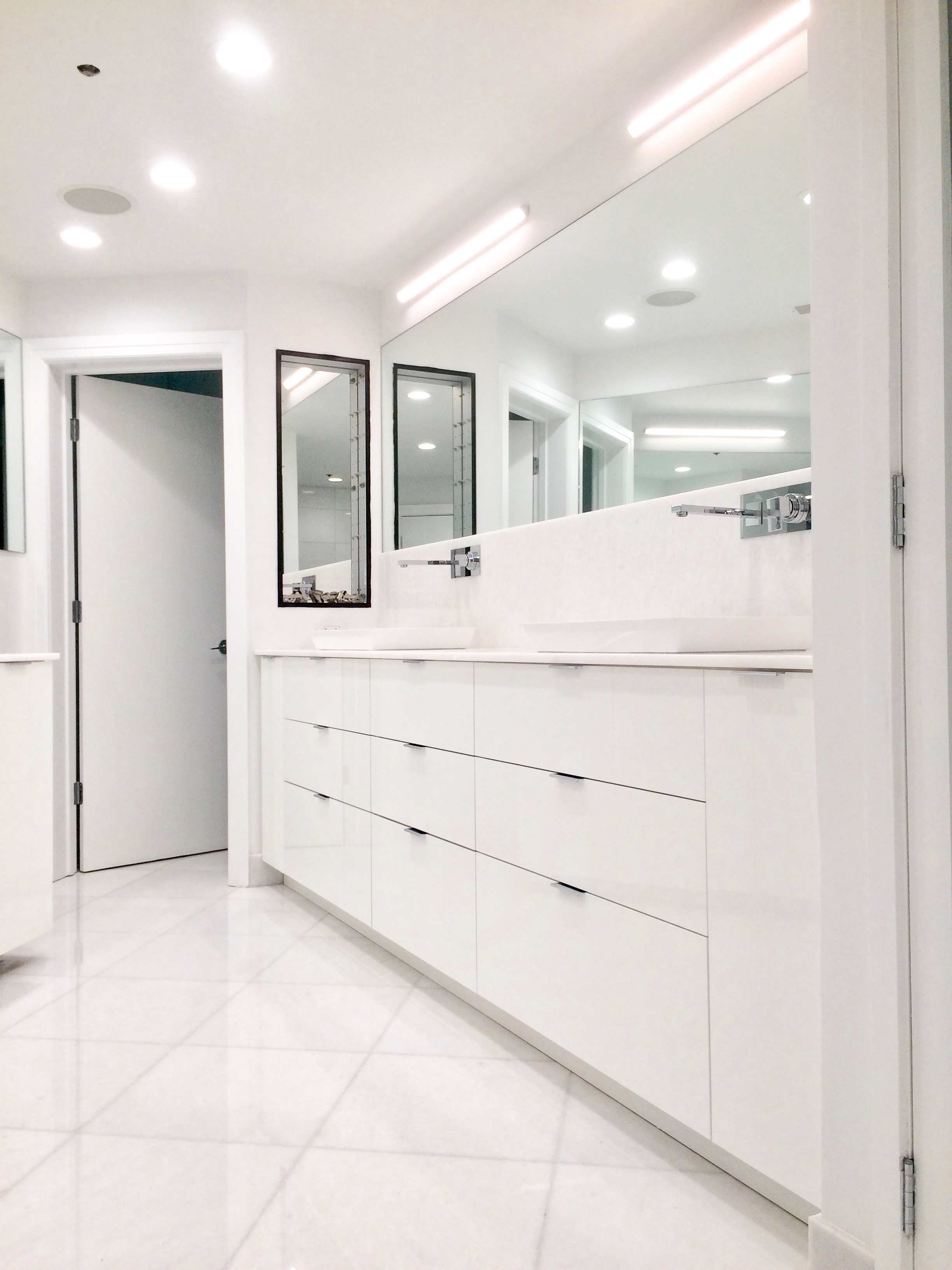 All-white floating vanity with backlit LED mirror surround